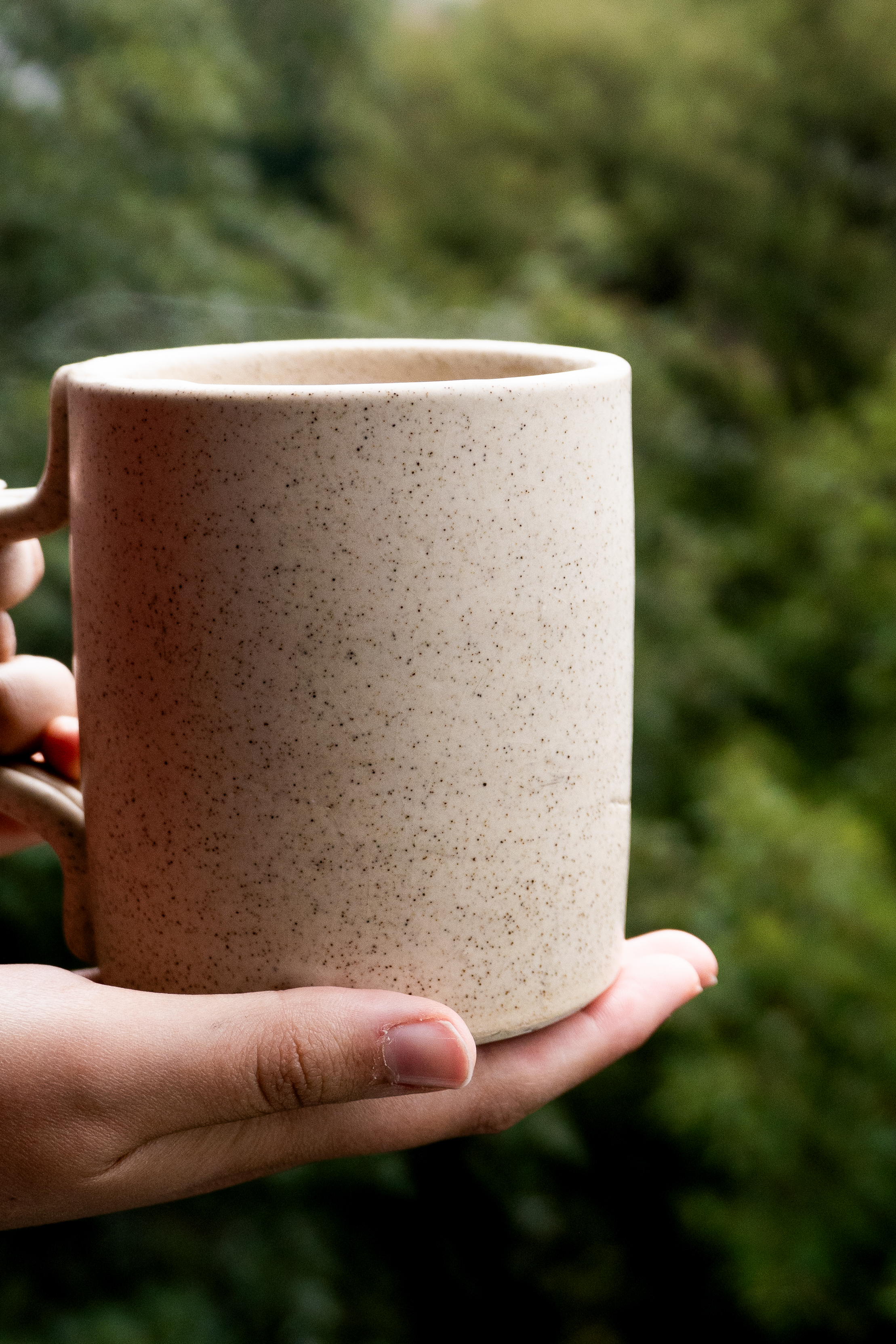 Hands holding a ceramic mug outdoors